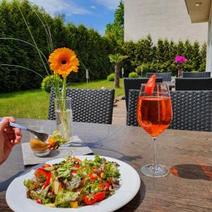 una mesa con un plato de ensalada y una copa de vino en Hotel Atlas Halle, en Halle an der Saale