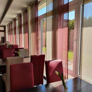 a dining room with red chairs and a table at Hotel Atlas Halle in Halle an der Saale