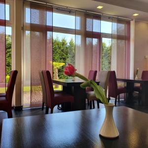 einen Tisch mit einer Vase mit einer roten Blume darauf in der Unterkunft Hotel Atlas Halle in Halle an der Saale