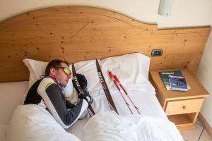 a man laying in a bed with skis at Bresidence Edelweiss in Valdidentro