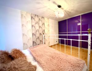 a bedroom with a bed with a purple wall at Apartament Monroe in Ustrzyki Dolne