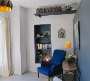 ein Wohnzimmer mit einem blauen Stuhl und einem Bücherregal in der Unterkunft les Lauriers in Caromb