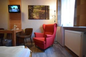 a hotel room with a red chair and a table at Gasthof Roseneck in Wallenfels