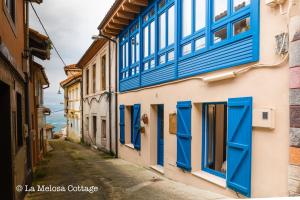 an alley with blue shutters on a building at La Melosa Cottage in Cudillero