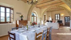 een eetkamer met een tafel met een witte tafeldoek bij Alborata 10, Emma Villas in Montalcino