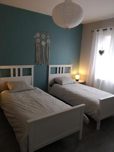 two beds in a bedroom with blue walls and a window at Au cœur de la Sologne in Romorantin