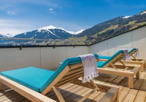 2 Stühle auf einem Balkon mit Bergen im Hintergrund in der Unterkunft Hotel Blü Gastein in Bad Hofgastein