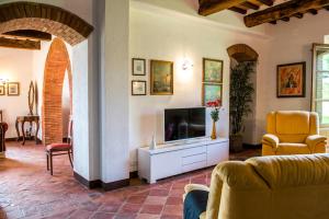 a living room with a television and an archway at BOSSONCINA 8&1, Emma Villas in Montepulciano