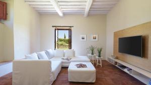 sala de estar con sofá blanco y TV de pantalla plana en CA MAGGIORE 10&2, Emma Villas en Castiglion Fibocchi