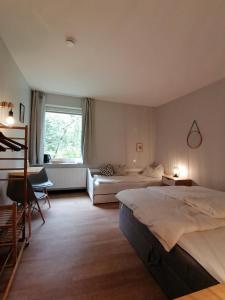 um quarto com 2 camas, um sofá e uma janela em Waldjugendherberge Uelsen em Uelsen