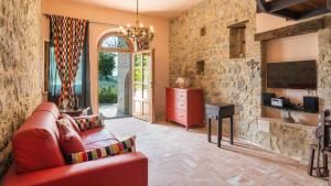 sala de estar con sofá rojo y TV en Casa Elia 6, Emma Villas, en San Casciano dei Bagni