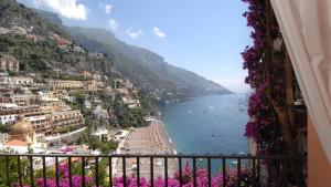 vistas a una playa con flores púrpuras en el balcón en CASA MARIA 6&2, Emma Villas, en Positano