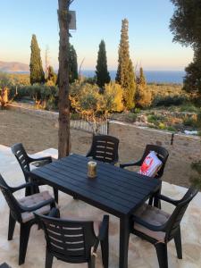 a black picnic table and chairs with a view of the ocean at Kamares Cave House 3 in Álika