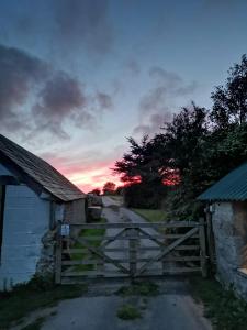 a barn with a gate next to a road at Penhallow House Glamping Retreat in Newlyn East