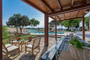 un patio al aire libre con pérgola de madera, mesas y sillas en CASALE BONAVENTURA 8, Emma Villas, en Ostra