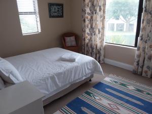 1 dormitorio con cama, ventana y alfombra en Trev's Place, en St Francis Bay