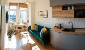 een woonkamer met een groene bank en een keuken bij Emerald Room in Toruń