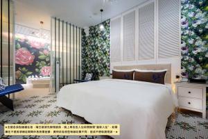 1 dormitorio con cama blanca grande y papel pintado con motivos florales en Birdman Motel, en Taichung