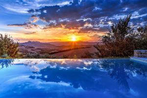 una piscina con tramonto sullo sfondo di CASALE DELLE LAVANDE 10, Emma Villas a Todi