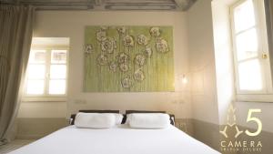 a bedroom with a white bed with a painting on the wall at Guest House A Via dei Pellegrini in Viterbo