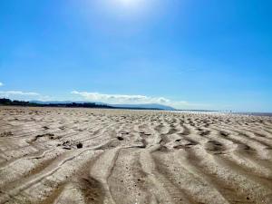 uma praia vazia com marcas de pneus na areia em Cumbrian Lodge em Seascale