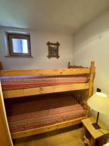 a room with a bunk bed with a table and a lamp at La Troïka in Notre-Dame-de-Bellecombe