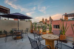 eine Terrasse mit Tischen, Stühlen und einem Sonnenschirm in der Unterkunft Casa Pandurata Luxury Apartments in Centro, San Miguel de Allende in San Miguel de Allende