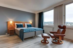 a bedroom with a bed and a chair and windows at Hotell Vic Porsgrunn in Porsgrunn +38 photos