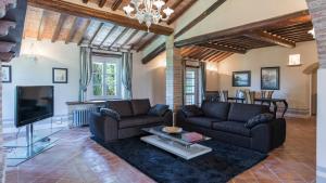sala de estar con 2 sofás y TV en Dimora Rovena 24, Emma Villas en Castiglione del Lago