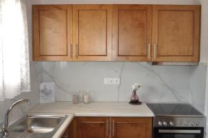 a kitchen with wooden cabinets and a sink at Vrachos Villas in Agia Paraskevi