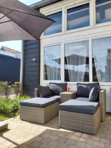 a patio with two wicker chairs and an umbrella at Dulce Tierra - vakantiewoning in Zoutelande
