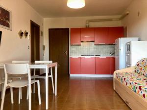 eine Küche mit roten Schränken sowie einem Tisch und Stühlen in der Unterkunft Residence Libertà in Grado
