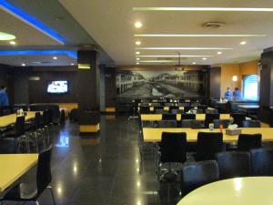 a dining room with tables and chairs and televisions at Hotel Kini Pontianak in Pontianak