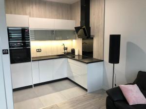 a kitchen with white cabinets and a black counter top at Apartament Plaza Premium in Słupca