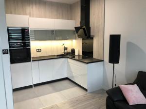 kuchnia z białymi szafkami i czarnym blatem w obiekcie Apartament Plaza Premium w Słupcy