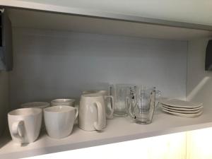 a shelf with cups and glasses and plates on it at Apartament Plaza Premium in Słupca