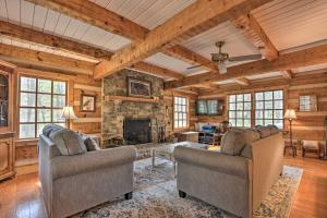 a living room with two chairs and a stone fireplace at Riversong Cabin with Fire Pit on North River in Slanesville