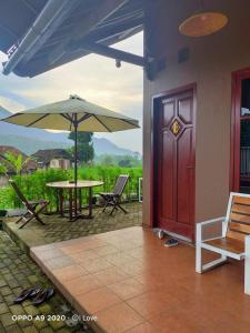 une terrasse avec une porte rouge, une table et un parasol dans l'établissement SUWON homestay, à Mojokerto