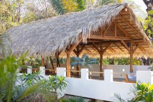 a pavilion with a thatched roof and a white fence at The Nomadic Hotel in Nosara
