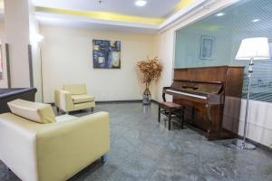 un soggiorno con pianoforte e sedia di Hotel Dan Inn Sorocaba a Sorocaba