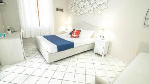 um quarto branco com uma cama e piso em azulejo branco em Hotel Il Perseo em Chiessi