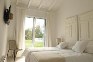 a white bedroom with a large bed and a window at El Pueblín de Ribadesella in Ribadesella +25 photos