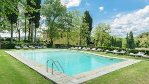 a swimming pool in a yard with chairs and a house at Poggerello 18, Emma Villas in Laterina