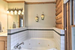 a bathroom with a tub and a mirror at Secluded Gaylord Cabin with Deck, Fire Pit and Grill! in Gaylord