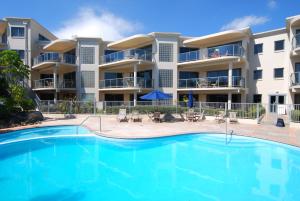 una piscina frente a un edificio de apartamentos en The Reef Beachfront Apartments, en Mount Maunganui