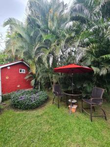 a patio with chairs and an umbrella and a red building at Cabaña Villa Victoria in Valle de Anton