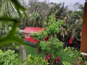 a red house with a red roof in a garden at Cabaña Villa Victoria in Valle de Anton