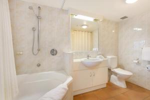 a bathroom with a tub and a sink and a toilet at Tropic Towers Apartments in Cairns