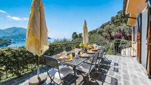 uma mesa com cadeiras e um guarda-sol numa varanda em Villa Baia Blu 12, Emma Villas em Camogli