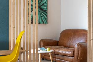 a living room with a brown leather couch and a table at Naéco Le Pouldu in Clohars-Carnoët
